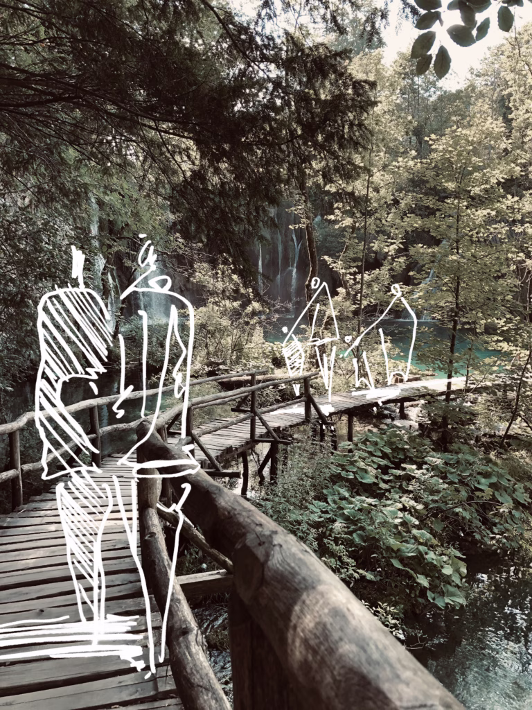 Art installation with white figures on a wooden walkway in the forest